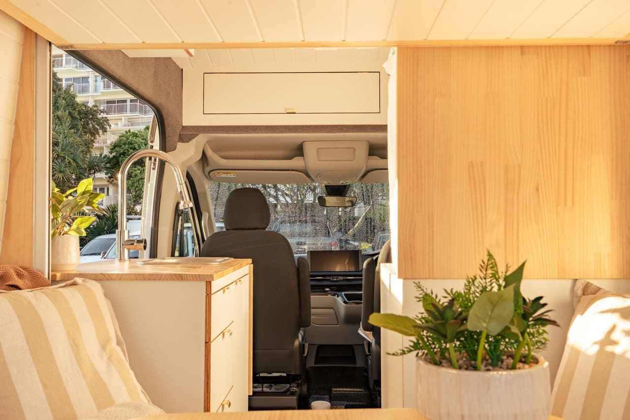 Timber-lined rear lounge looking forward past the kitchen to the cab